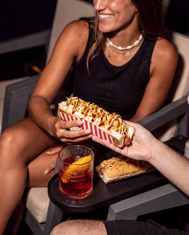 Una chica en su butaca con pochoclo y un trago con naranja